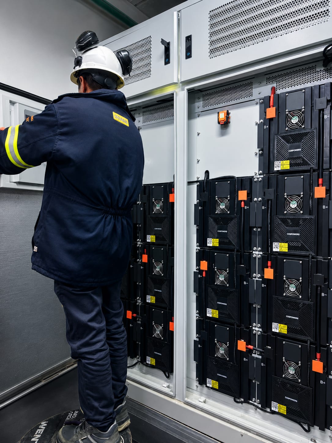 Operario trabajando frente a un tablero de rectificación de corriente continua en una sala eléctrica